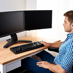 **

Ergonomic home office setup. A person sitting in a fully adjustable ergonomic chair, with proper lumbar support. The monitor is at eye level, supported by a monitor arm. Hands resting comfortably on a keyboard with wrist rest. Good lighting and a footrest visible. The overall scene conveys a healthy and comfortable working environment.

**